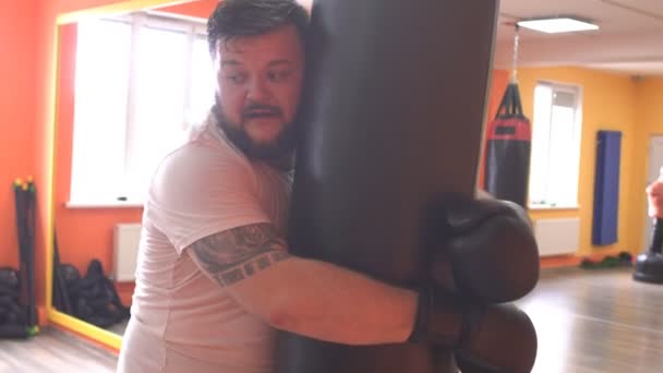 Wet and sweaty, bearded caucasian man boxing a punching bag in training at the gym - Materiaali, video