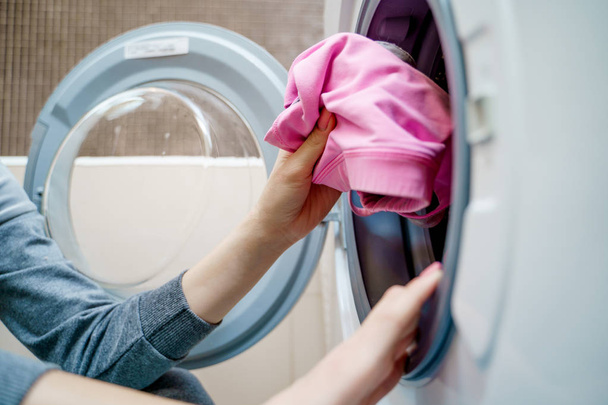 Womens hands putting laundry in washing machine - 写真・画像