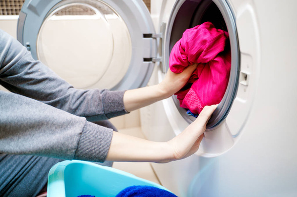 Photo of woman hands putting dirty clothes in washing machine . - Photo, Image