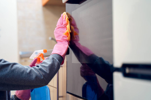 Foto de mãos femininas em luvas de borracha com pano e detergente microondas de limpeza
. - Foto, Imagem