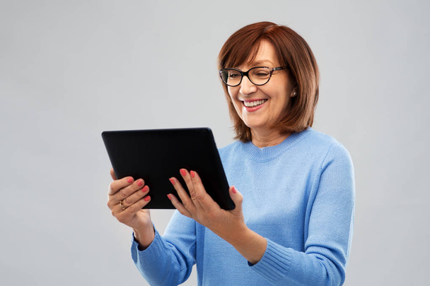 senior woman in glasses using tablet computer - 写真・画像