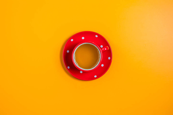 Красный в белом пунктирной чашкой чая на желтой поверхности
 - Фото, изображение
