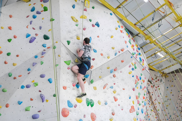 Sportsmen climbs boulder in a gym. A successful man climbing on climbing wall.                                         - Photo, Image