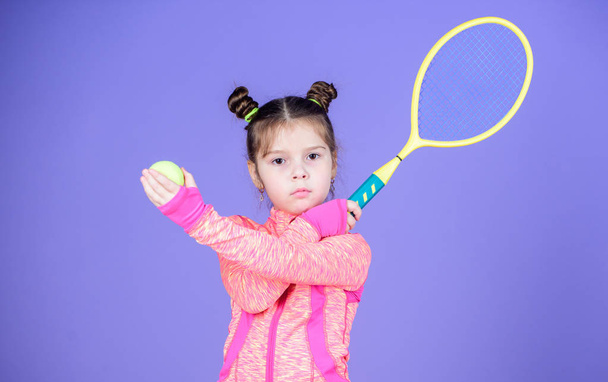 Active games. Sport upbringing. Small cutie likes tennis. Sport equipment store. Play tennis for fun. Little baby sporty costume play tennis game. Girl cute child double bun hairstyle tennis player - Foto, Bild
