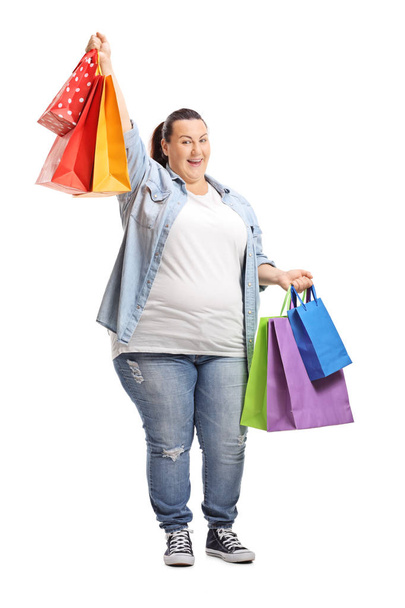 Full length portrait of a happy plus size woman holding shopping bags isolated on white background - Foto, immagini