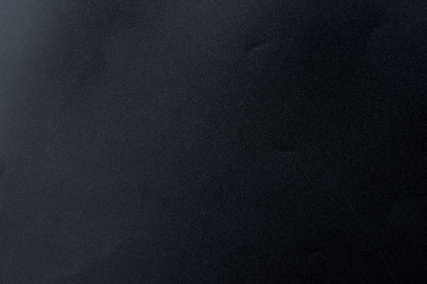Чорний грубий текстурований фон, освітлений тьмяним світлом під кутом
. - Фото, зображення
