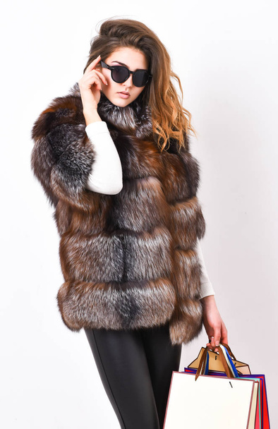 Woman shopping luxury boutique. Lady hold shopping bags. Discount and sale. Buy with discount on black friday. Shopping or birthday gift. Girl wear sunglasses and furry coat shopping white background - Zdjęcie, obraz