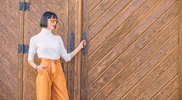 Woman walk in loose pants. Woman fashionable brunette stand outdoors wooden background. Girl with makeup posing in fashionable clothes. Fashionable outfit slim tall lady. Fashion and style concept - Φωτογραφία, εικόνα