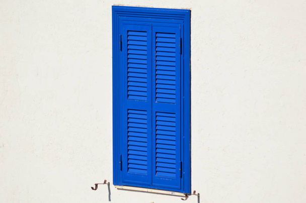 Een blauwe sluiter op een witte muur - Foto, afbeelding