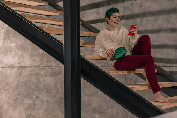 Stylish young woman reading online news on her red phone - Fotografie, Obrázek