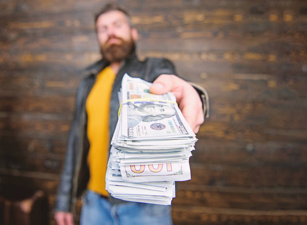 Guy mafia dealer with cash profit. Man give cash money bribe. Richness and wellbeing. Mafia business. Man brutal bearded hipster wear leather jacket and hold cash money. Illegal profit and black cash - Фото, изображение