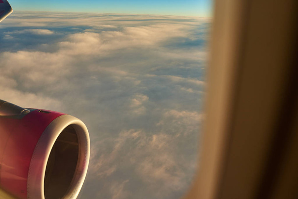 Widok przez okno z reflektorem turbiny samolot leciał nad chmurami - Zdjęcie, obraz
