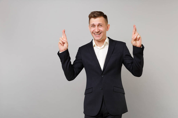 Glimlachend jonge zakenman in klassieke pak houden vingers kruisen - Foto, afbeelding