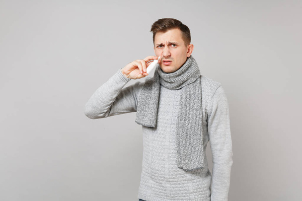 Abominato giovane uomo in maglione grigio, sciarpa che tiene gocce nasali ne
 - Foto, immagini