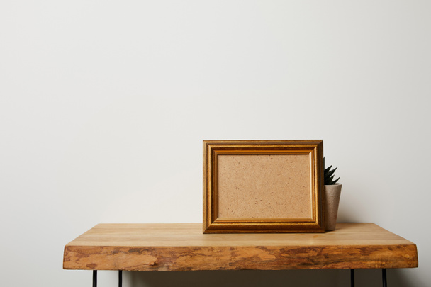 frame near plant on wooden table at home - Foto, Imagen