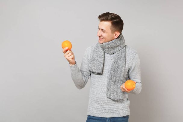 Приятный молодой человек в сером свитере, с шарфом, смотрящим на ору
 - Фото, изображение