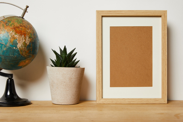 blank frame near globe and green plant in pot  - Foto, Bild