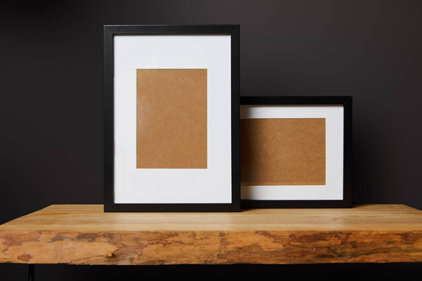 black blank frames on wooden table at home - Foto, afbeelding
