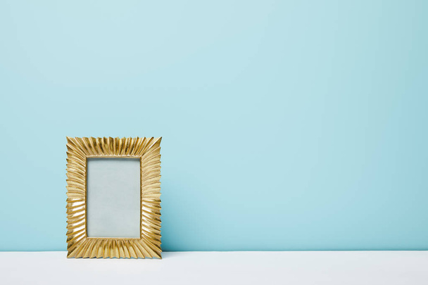 golden frame on white surface near blue wall - Foto, Imagem