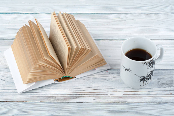 Open book, coffee cup and snack on wooden table background. - Фото, изображение