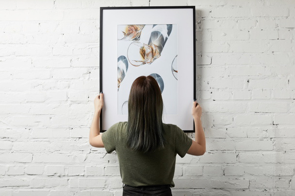 back view of woman holding drawing in black square frame - Foto, Imagen