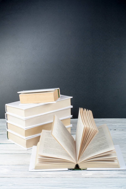 Open books on wooden table, black board background. Back to school. Education business concept. - Photo, image