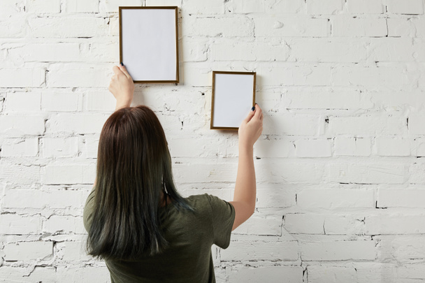 back view of woman holding blank frames in hands - Foto, Imagen