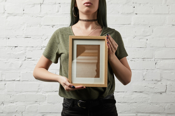 обрезанный вид женщины, стоящей и держащей пустую квадратную рамку в руках
 - Фото, изображение