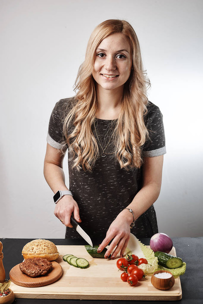 Blond smiling woman making burger at table - Photo, image