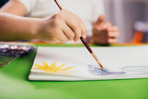cropped image of boy drawing by painting brush at table - Valokuva, kuva