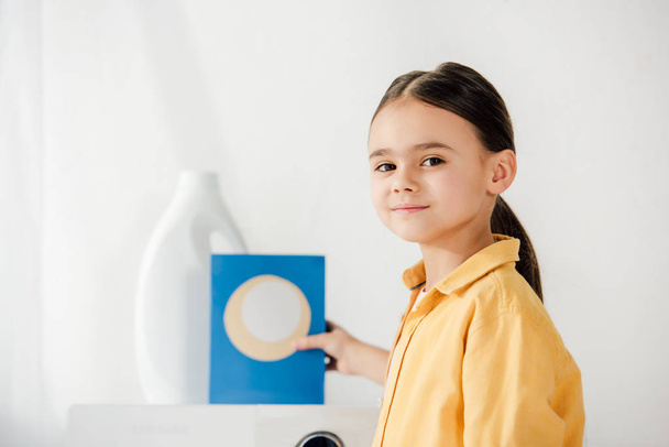 selective focus of child with washing powder in laundry room - Φωτογραφία, εικόνα