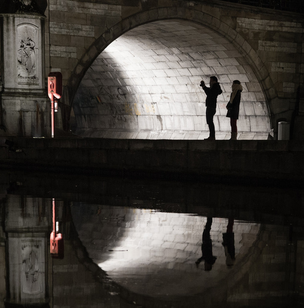 Silhouetten und Spiegelungen von Touristen unter einer mittelalterlichen Brücke - Foto, Bild