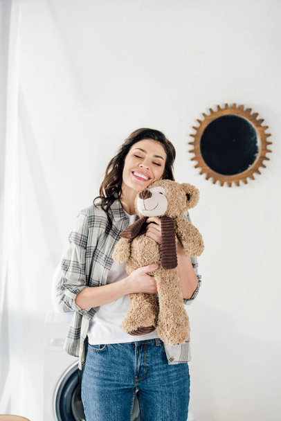 Kobieta trzyma niedźwiedź zabawka i uśmiechając się w domu - Zdjęcie, obraz