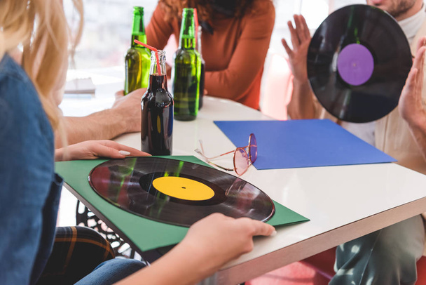 selective focus of friends holding vinyl and glass bottles with drink  - Foto, Bild