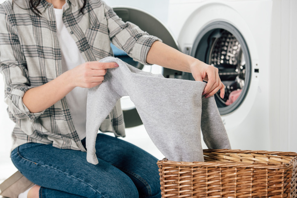 vue recadrée de la femme tenant des vêtements près de la laveuse dans la buanderie
 - Photo, image