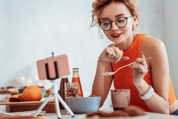 Positive good looking woman showing a spoon with muesli - Photo, Image