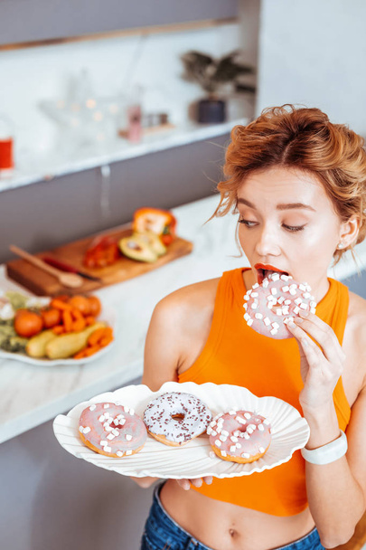 Beautiful young woman holding a plate with donuts - Foto, afbeelding