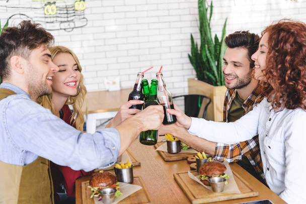 красиві і красиві друзі вітають зі скляними пляшками в кафе
  - Фото, зображення