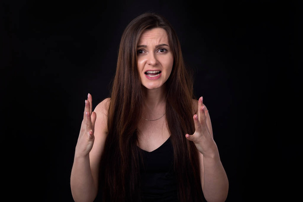 Irritated, angry woman brunettes on a dark background. Negative emotions. - Zdjęcie, obraz