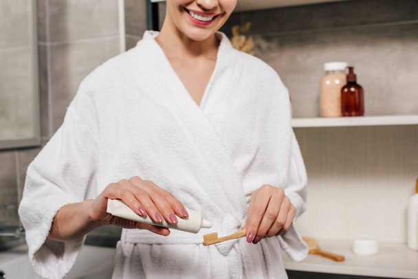 vista ritagliata della donna che applica dentifricio sullo spazzolino da denti dal tubo in bagno
 - Foto, immagini