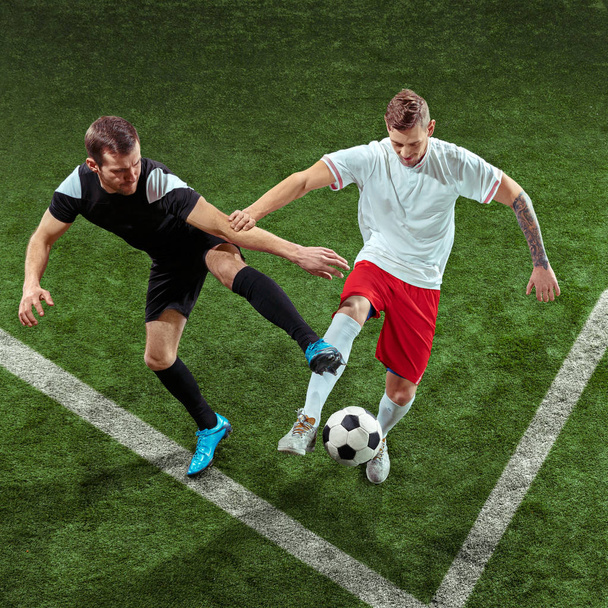 Футболісти грають у м'яч на фоні зеленої трави
 - Фото, зображення