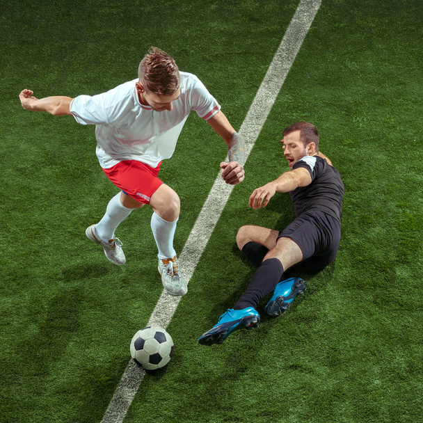 Футболисты играют в мяч на зеленом фоне травы
 - Фото, изображение