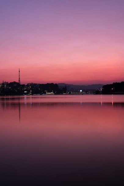 der zauberhafte Sonnenuntergang am See, in dem sich die Stadt spiegelt - Foto, Bild