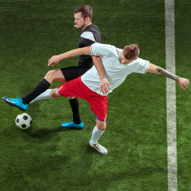Football players tackling ball over green grass background - Фото, зображення