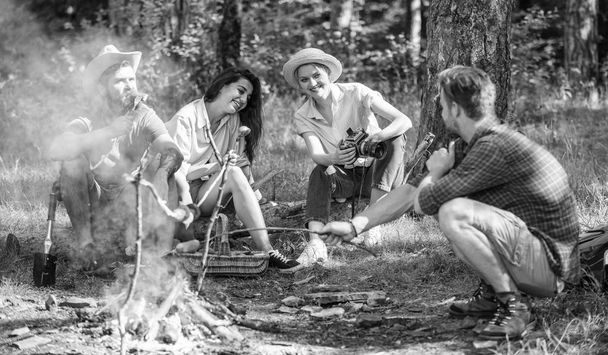 Hikers sharing impression of walk and eating. Weekend hike. Picnic with friends in forest near bonfire. Company having hike picnic nature background. Tourists with camera relaxing checking photos - Foto, imagen