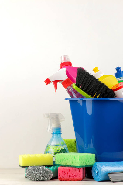 Flaschen mit Waschmittel und Reinigungswerkzeug in einem Eimer auf hellem Hintergrund. Reinigung. Reinigungsmittel. - Foto, Bild