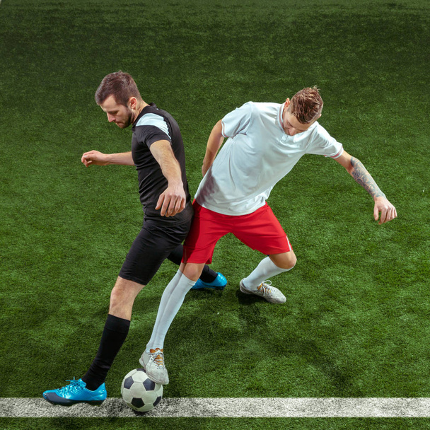 Jugadores de fútbol abordando pelota sobre fondo de hierba verde
 - Foto, imagen
