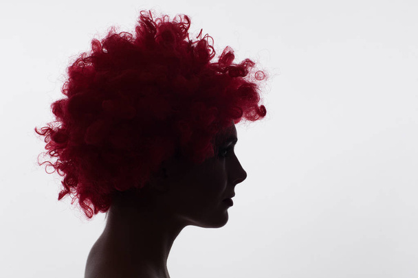 Silhouette of a woman in a red curly wig - Фото, зображення