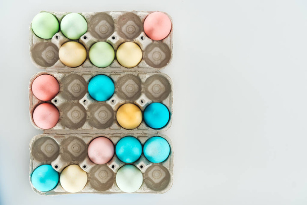 vista superior de coloridos huevos de Pascua en recipientes de papel aislados en gris
 - Foto, imagen
