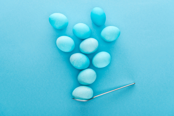 вид сверху на традиционные пасхальные яйца на ложке, изолированные на голубом
  - Фото, изображение
